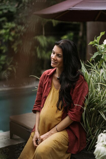 Young pregnant woman with long dark hair in a tropical location