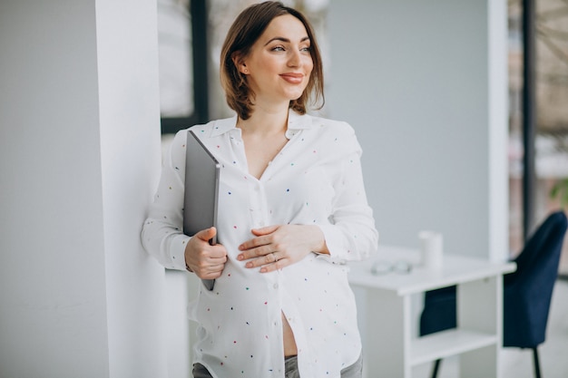 Young pregnant woman working on computer out of the office