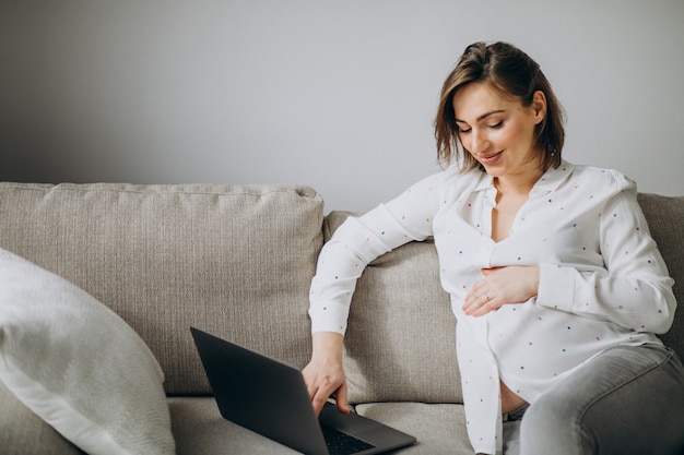 Foto gratuita giovane donna incinta che lavora al computer portatile a casa