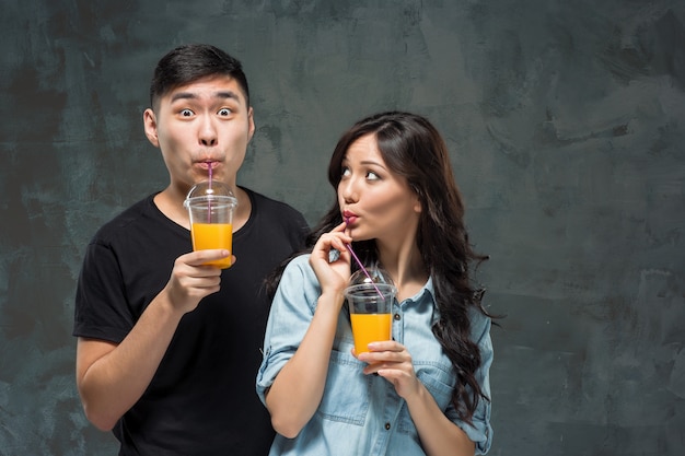 A young pretty Asian couple with a glasses of Orange juice