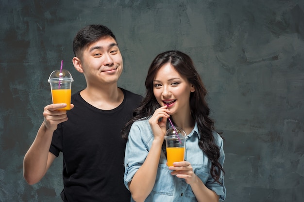 A young pretty Asian couple with a glasses of Orange juice