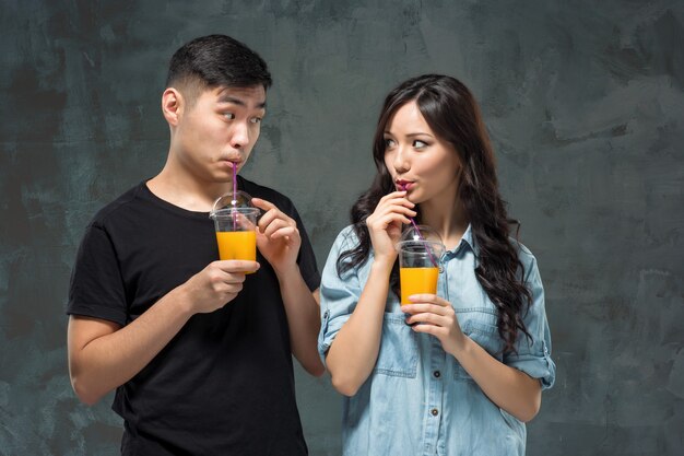 Молодая красивая азиатская пара с бокалами апельсинового сока
