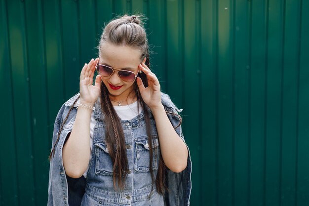 テキストのための場所でシンプルな濃い緑の壁にメガネのデニムの服のかなり魅力的な少女。