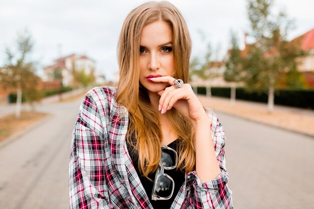 Young pretty blonde cheerful girl with surprised face looking, posing in countryside in warm sunny spring day. Funny emotional face.