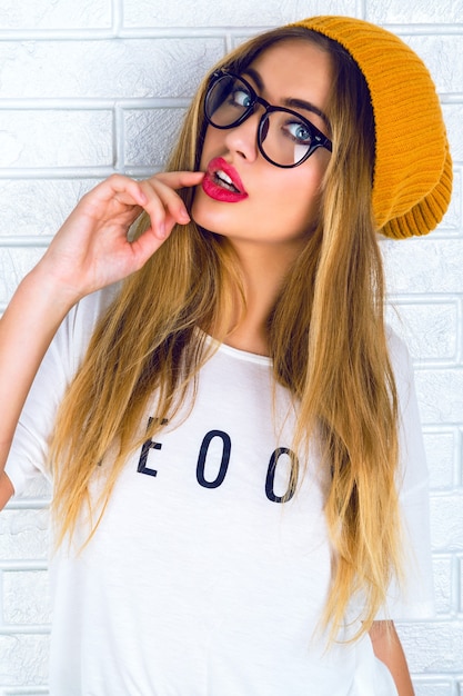 Young pretty blonde woman with bright sexy lips, wearing glasses and hat