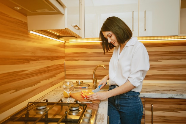 Foto gratuita giovane e bella mora in piedi in cucina con l'arancio