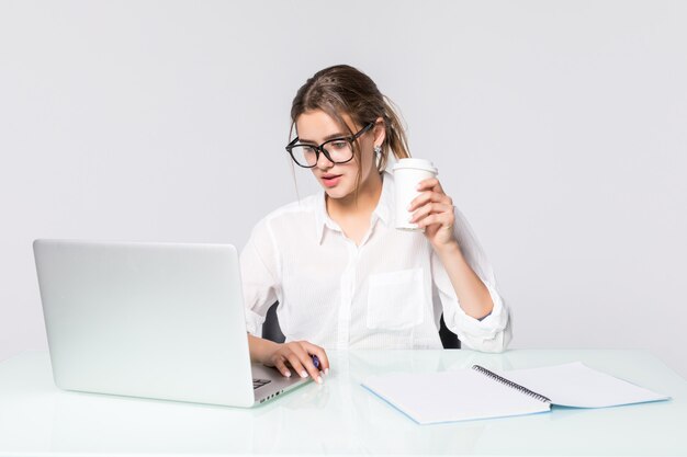 흰색 배경에 고립 된 사무실 책상에서 노트북으로 젊은 예쁜 사업 여자