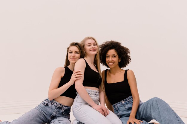 Young pretty caucasian afro woman in casual clothes cheerfully posing together on white background Diverse ethnicity lifestyle