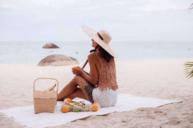 Young pretty caucasian tanned fit woman in knitted clothes and hat on beach