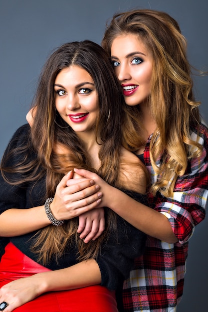 Young pretty couples of womans posing, fashion trendy elegant portrait, brunette and blonde, best friends hugs, color matching clothes, bright sexy make up, long hairs.