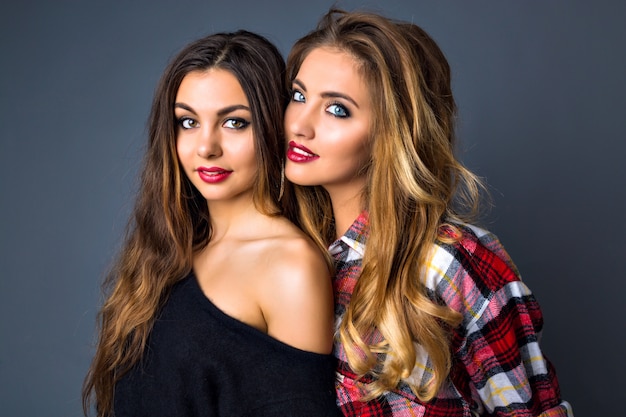 Young pretty couples of womans posing, fashion trendy elegant portrait, brunette and blonde, best friends hugs, color matching clothes, bright sexy make up, long hairs.