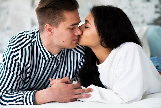 Free photo young pretty ethnic woman kissing lying man