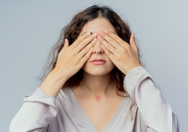 若いきれいな女性サラリーマンは白で隔離の手で目を覆った