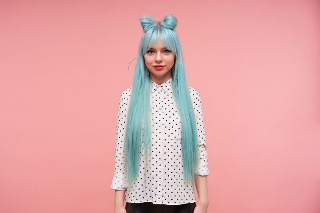 お団子の髪型がうまくいけば指を交差させ ポーズをとっている間フォーマルな服を着て彼女の下唇をエキサイティングに噛む美しい若い長い髪の女性の肖像画 無料の写真