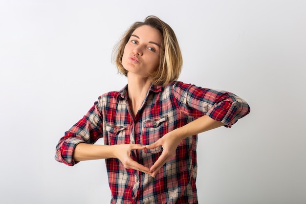 Young pretty funny emotional woman in checkered shirt posing isolated on white studio wall, showing love gesture