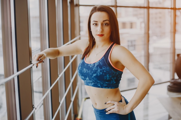 Free photo young and pretty girl in a blue sports suit is engaged in sports in the gym