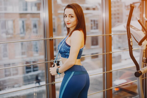 young and pretty girl in a blue sports suit is engaged in sports in the gym