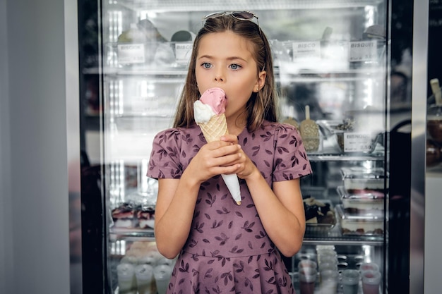Young pretty girl in a dress, eating ice cream in a cafe.