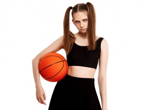 Young pretty girl posing with basketball, isolated on white wall