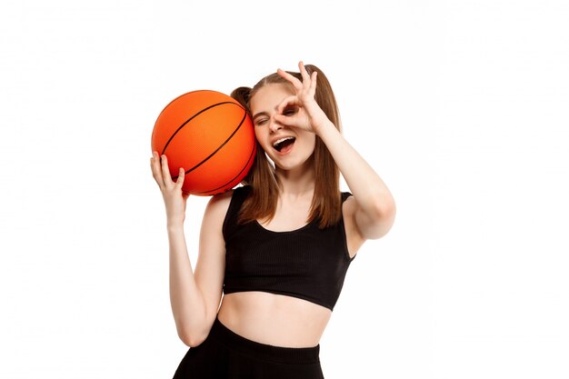 Young pretty girl posing with basketball, isolated on white wall