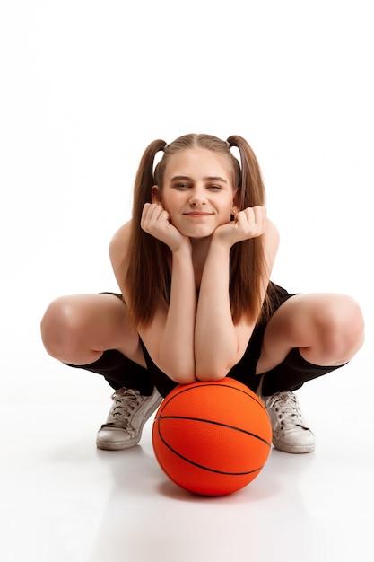Young pretty girl posing with basketball over white wall