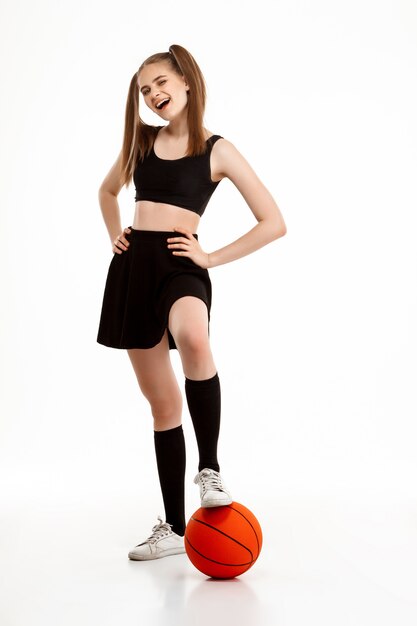 Young pretty girl posing with basketball over white wall