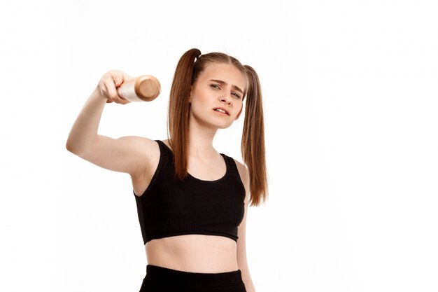 Young pretty girl posing with bat, isolated on white wall