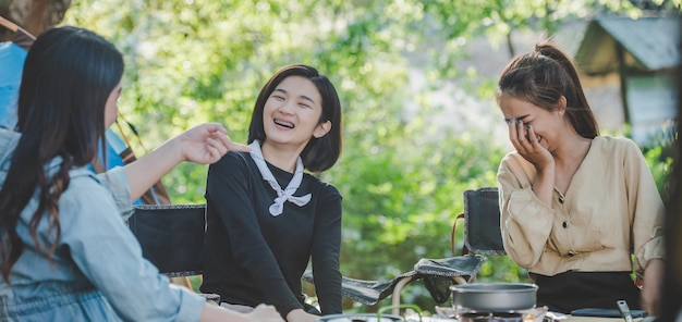 Young pretty girl put an egg on pan while camping with her friends cooking easy meal in nature park They are enjoy to discussion and laugh with fun together copy space