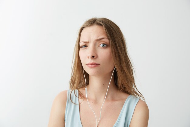 Young pretty girl raise brow listening to streaming music in headphones .