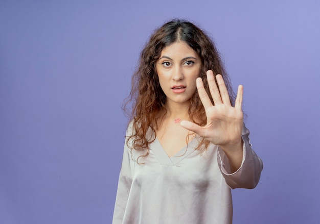 young pretty girl showing stop gesture isolated on blue wall