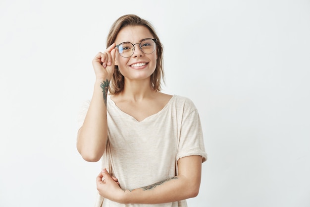 Young pretty girl smiling correcting glasses .