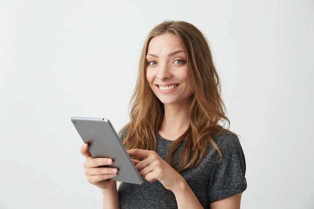 Young pretty girl smiling surfing web browsing internet on tablet .