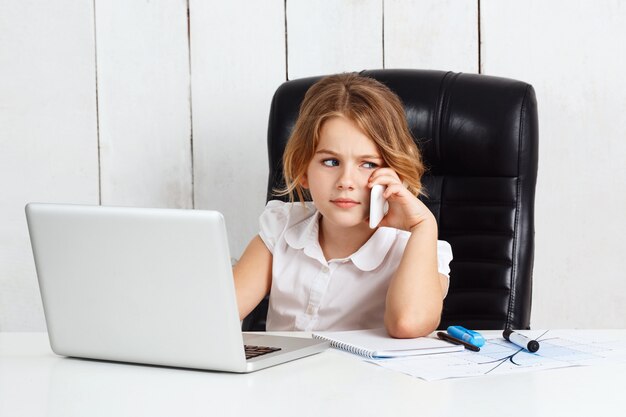 Young pretty girl speaking phone at working place in office.