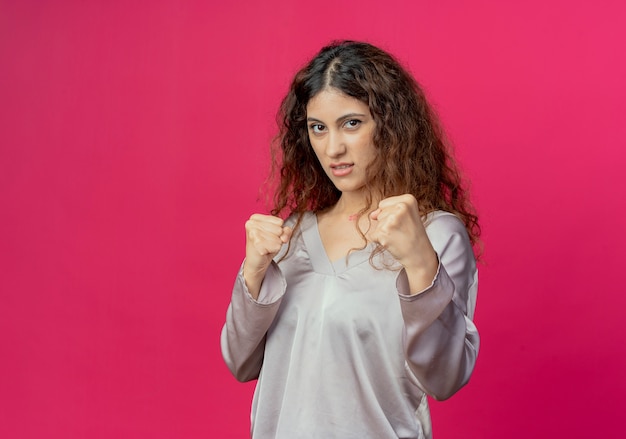 young pretty girl standing in fighting pose isolated on pink wall