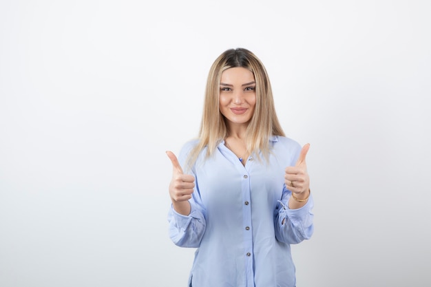 young pretty girl standing and giving thumbs up on white. 