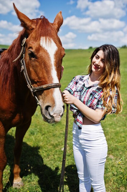 Young pretty girl stay with horse on a field at sunny day