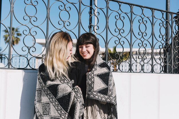 Young pretty girlfriends cuddling in plaid