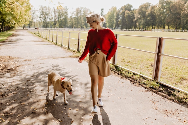 Young pretty lady playing with her dog in the park. Lovely blonde and white labrador having good time together.