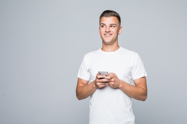 Молодой симпатичный мужчина в белой футболке, изолированные на белом, держит телефон в руках