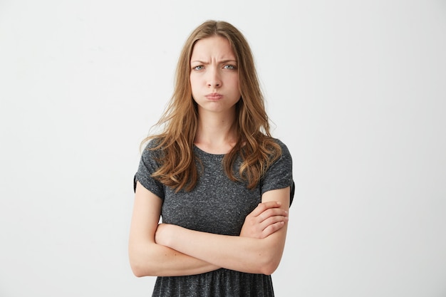 Foto gratuita giovane ragazza piuttosto offesa con la faccia buffa accigliata. braccia incrociate.