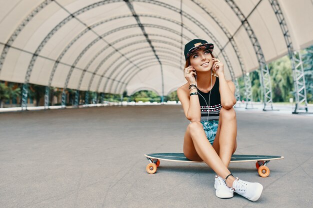 Young pretty smiling girl with a longboard