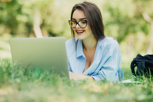 Young pretty smiling woman using laptop in citypark at sunny day