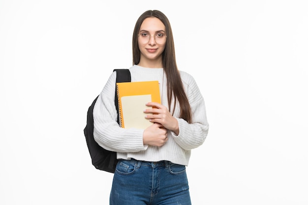 バックパックと練習帳を持つ若いきれいな学生女性。白い壁に分離