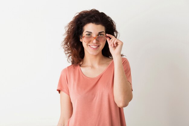 Young pretty stylish woman holding glasses, curly hair, smiling, positive emotion, happy, isolated, pink t-shirt