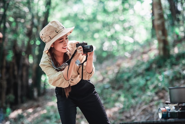 Young pretty taking photo by digital camera she looking picture and smile with happy while camping in forest Young Asian group women travel outdoor camping