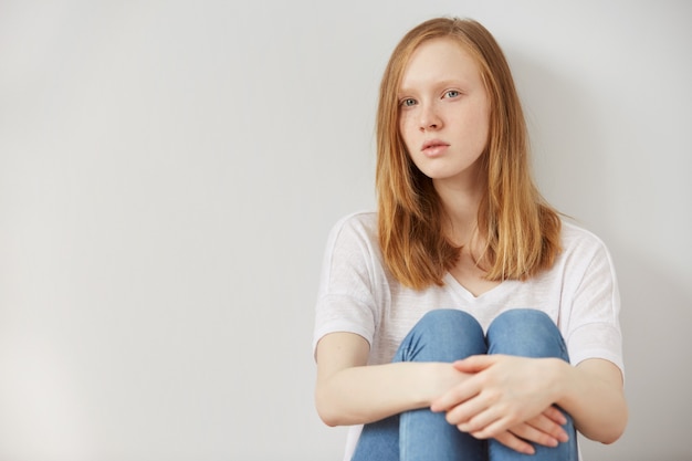 Free photo young pretty teenage girl sitting on floor at home despair sad alone