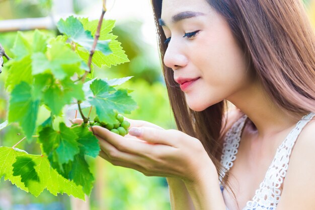 Young pretty woman appreciate the grape tree happily