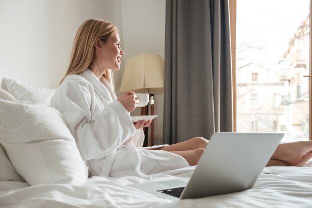 Young pretty woman in bathrobe drinking coffee