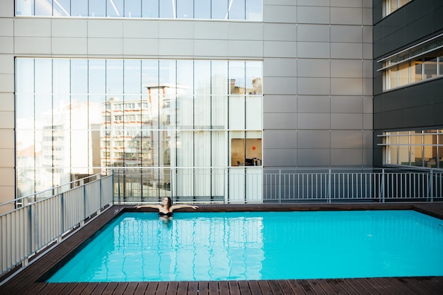 Young pretty woman in black swimsuit relaxes at the edge of the pool