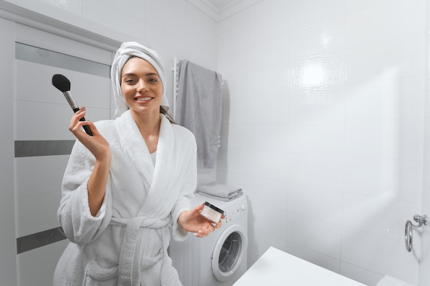 Young pretty woman doing face makeup at home